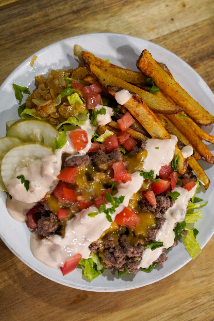 Animal Style Venison Burger Bowls with ground venison, crispy fires, caramelized onions, diced tomatoes and pickles.